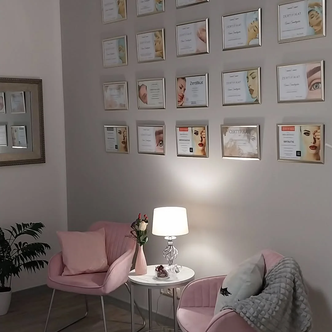 Der Warteplatz im Atelier: zwei rosa Samtsessel vor einer Wand mit gerahmten Zertifikaten